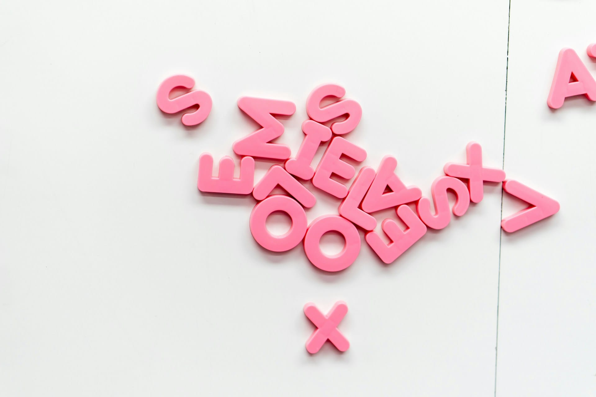 An image of several magnetic pink letters strewn out over a white table to indicate the creation of power words.